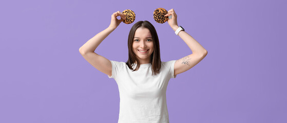 Funny young woman with tasty cookies on lilac background