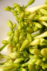 A close-up of a pile of fresh, raw papaya flowers (Carica papaya), mostly green with white tips, some still in bud form while others have bloomed. These flowers are commonly used in cooking 