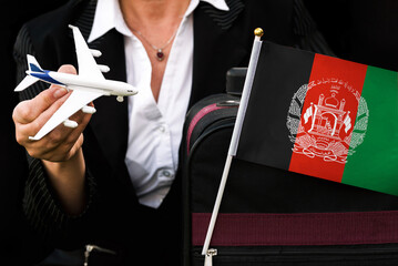 business woman holds toy plane travel bag and flag of Afghanistan

