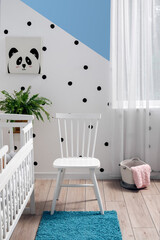Interior of stylish children's bedroom with crib, chair and picture