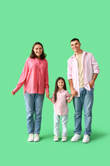 Fototapeta premium Little girl with her parents holding hands on green background