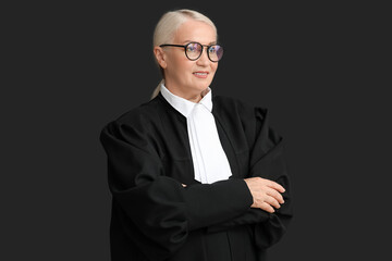 Mature female judge with crossed arms on black background