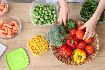 Female hands with fresh and frozen vegetables on wooden table