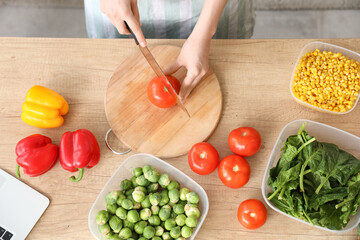 Woman cutting fresh tomatoes for freezing on wooden table