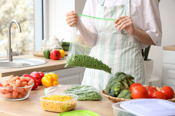 Woman holding plastic bag with green peas for freezing in kitchen