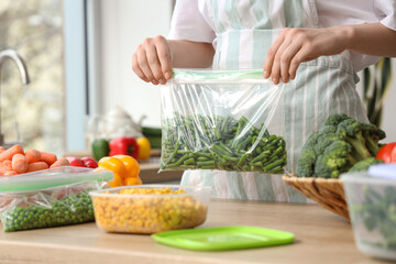 Woman holding plastic bag with green beans for freezing in kitchen