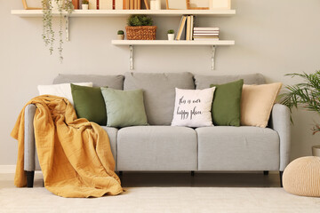Comfortable sofa with pillows near grey wall