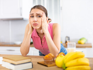 Housewife suffering from headache while preparing breakfast in kitchen