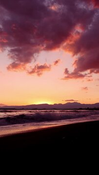 夕暮れの砂浜に打ち寄せる波（縦型ビデオ）