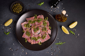 tuna carpaccio - slices of fresh raw tuna fillet on black ceramic plate