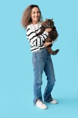 Happy mature woman with cute cat on blue background