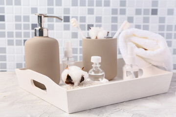 Tray with bath supplies on table against grey tile wall