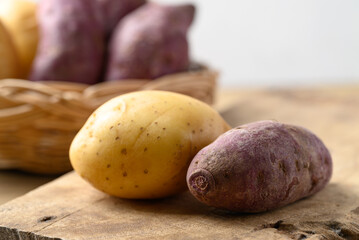 Raw potatoes and purple sweet potatoes on wooden table with white background, Food ingredient