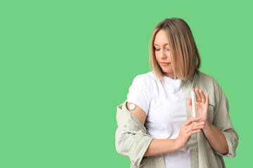 Woman with glucose sensor and lancet pen on green background. Diabetes concept