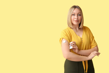 Woman with blood sugar sensor and glucometer on yellow background. Diabetes concept