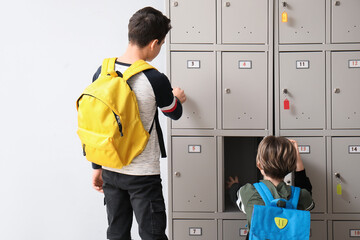 Little schoolboys opening their lockers at school, back view