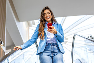 Young professional in a sleek suit ascends an urban escalator, her smartphone in hand. With a...
