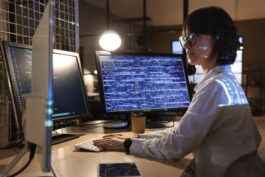 Young female programmer working with computer in office at night