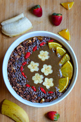 Healthy Raw Cacao chocolate smoothie bowl topping with cacao nibs and cacao granola goji berry banana and orange