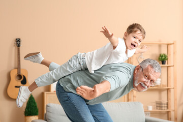 Happy grandfather with his cute little grandson having fun together at home