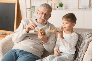 Grandfather and his cute little grandson playing with wooden toys at home