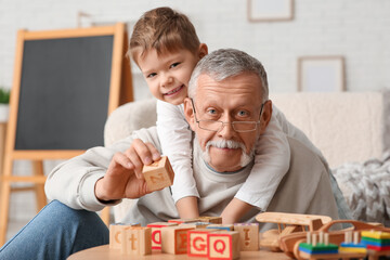Happy grandfather playing with his cute little grandson at home