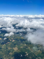 Aerial view of the clouds in the blue sky above the ground. View from an airplane window. Toronto, Canada. 