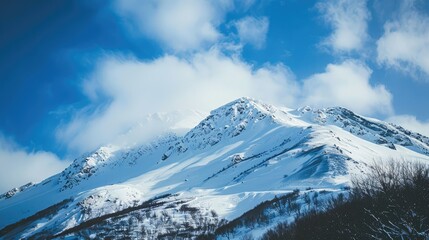 Obraz premium Mountain covered in snow under a clear blue sky with white clouds