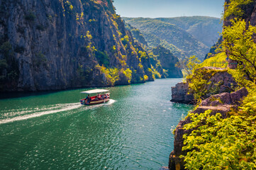 Wonderful spring view of Matka Canyon with small cruise boat. Sunny morning scene of North Macedonia, Europe. Traveling concept background.