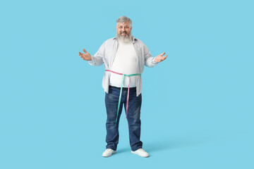 Overweight mature man with measuring tapes on blue background. Weight loss concept