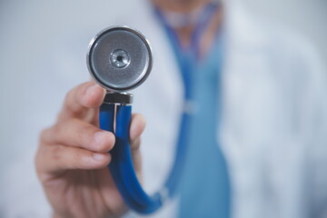 Senior doctor wearing white coat standing holding stethoscope in hands. Older male physician healthcare professional showing medical equipment ready to listen lungs or heart concept. Close up view