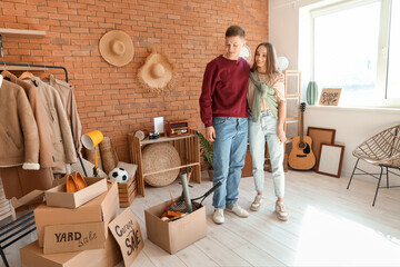 Young couple hugging in room of unwanted stuff. Yard Sale