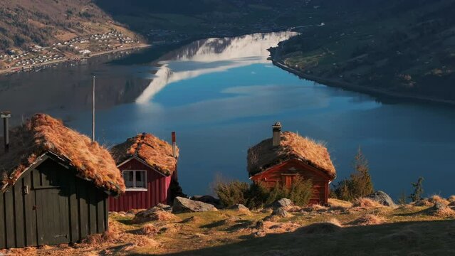 Valley glacier revealed from idyllic Norway mountainside cabins in sunset; drone