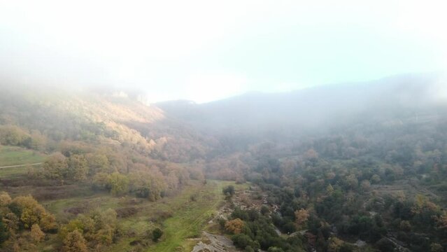 Osona's autumn landscape at sunrise, fog gently covering the hills, aerial view