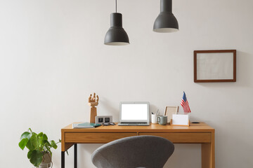Interior of stylish office with workplace, laptop and USA flag near white wall