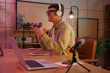 Young man with headphones and microphone recording podcast in studio