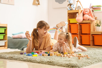 Nanny and little girl playing with cubes at home