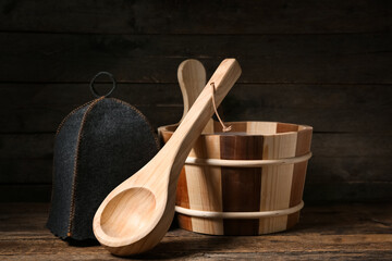 Ladle, bucket and felt hat for sauna on wooden background