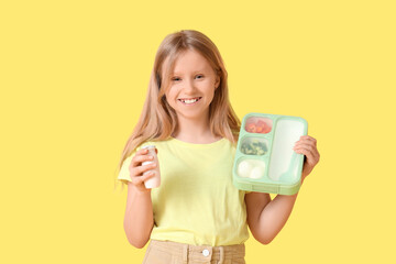 Happy girl with school lunchbox and drink on yellow background