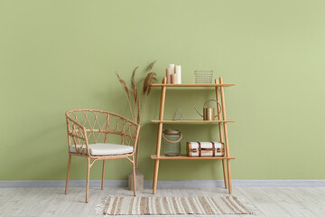 Shelving unit, suitcase and armchair near green wall in stylish room
