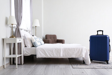 Interior of hotel room with suitcase near bed