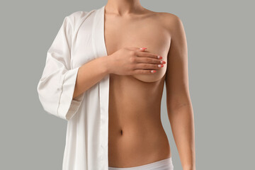 Young woman in robe covering her breast on light background, closeup