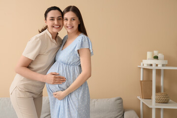 Young pregnant woman with doula hugging at home