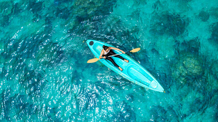 Aerial view of a woman and a young man kayaking on clear blue waters at Andaman Island. She does water sports activities.	

