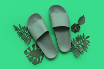 Composition with stylish flip-flops and paper palm leaves on green background