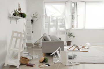 Interior of messy living room with sofa, shelves and plants