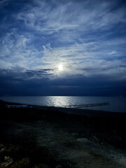 Moon over the lake. Full moon in the clouds. Kyrgyzstan, Lake Issyk-Kul