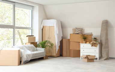 Cardboard boxes with furniture in room on moving day