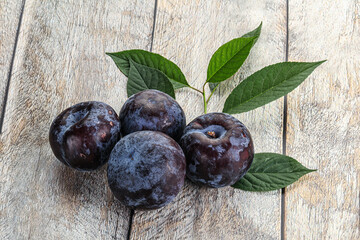 Raw purple plums heap with leaves