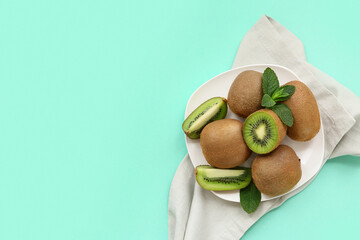 Plate with fresh kiwi and mint on turquoise background